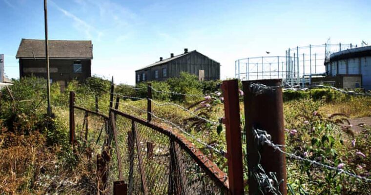 Brownfield site with disused buildings and wire fence